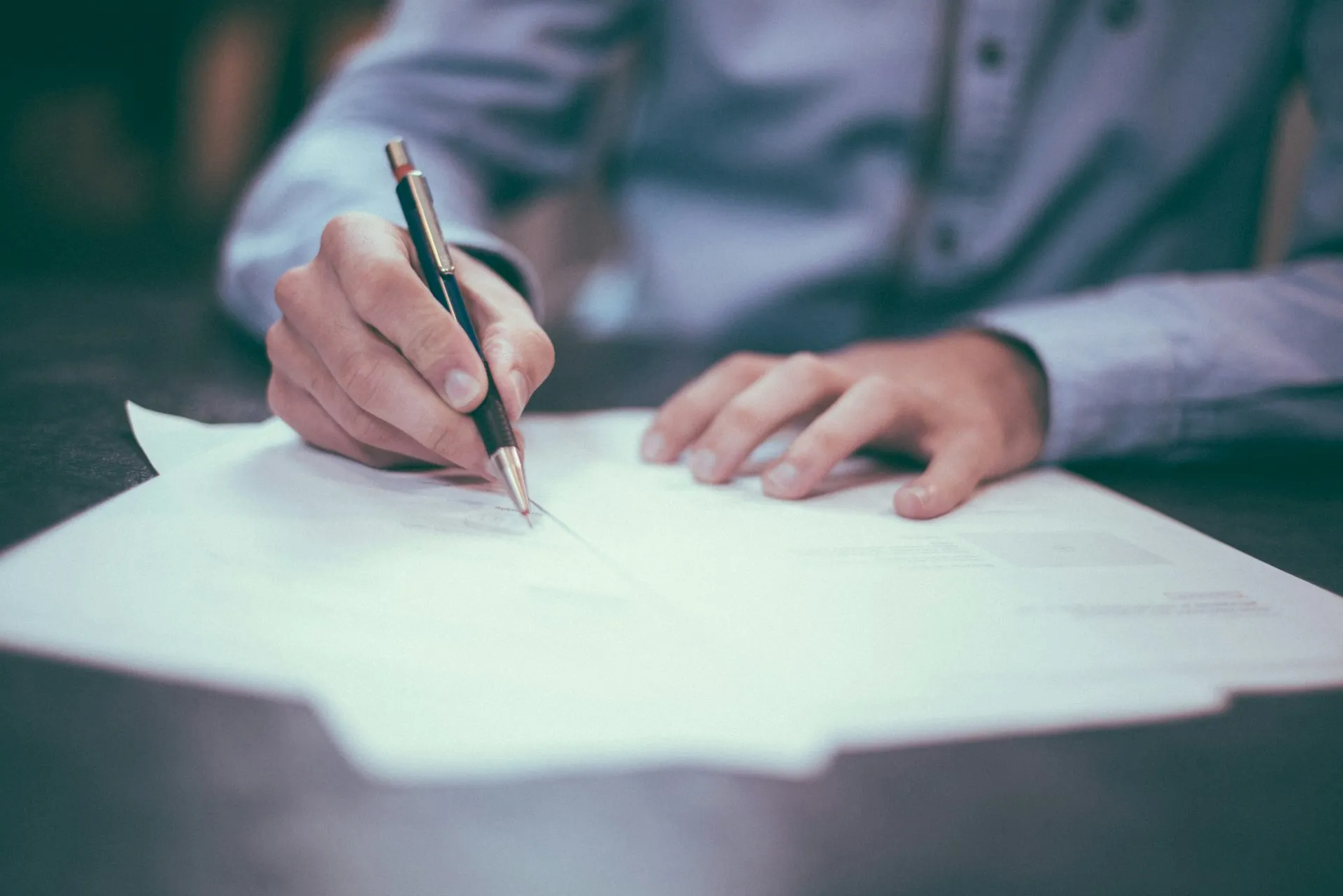 A person writing on documents at a desk.